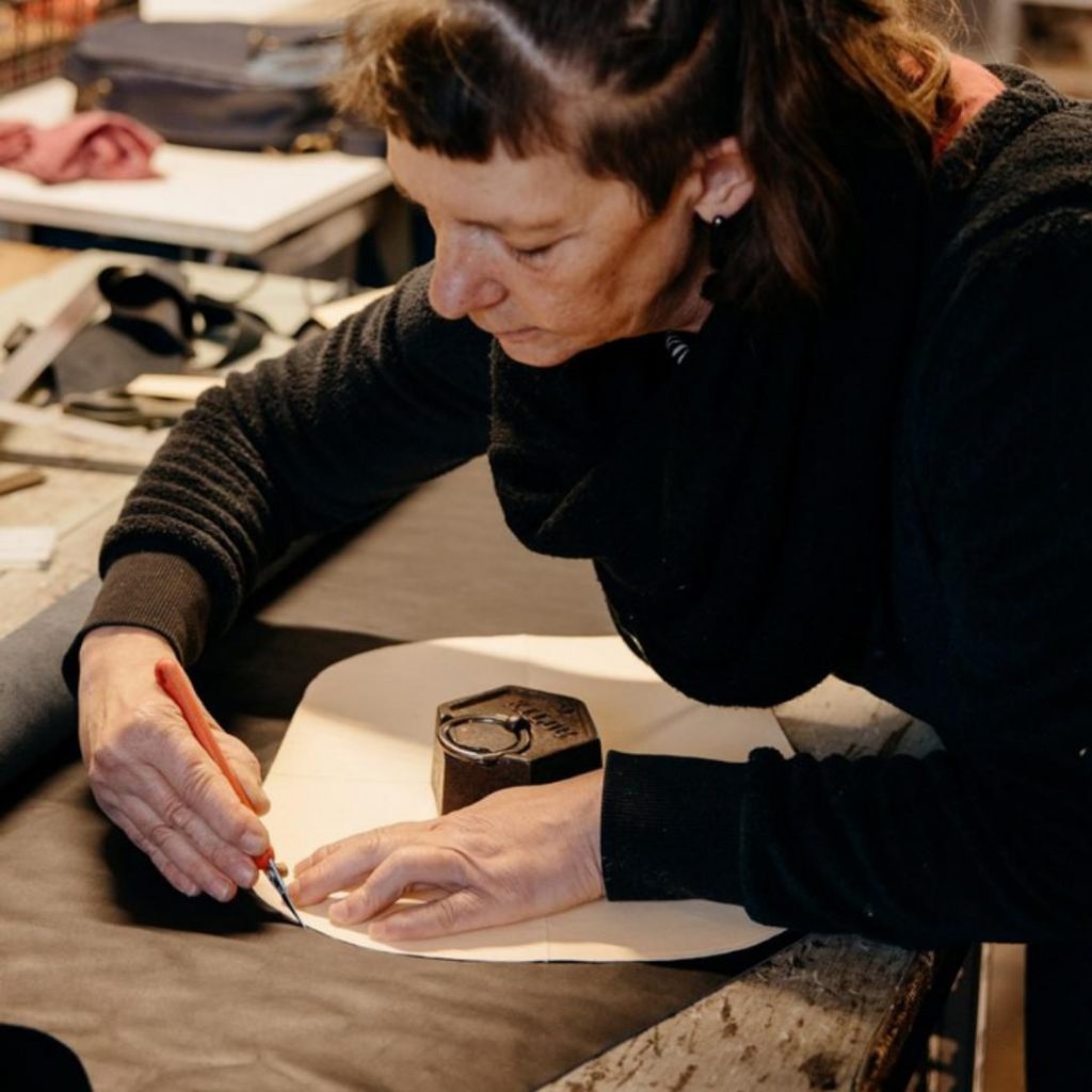 Découpe d'une pièce de cuir dans un atelier de maroquinerie artisanale